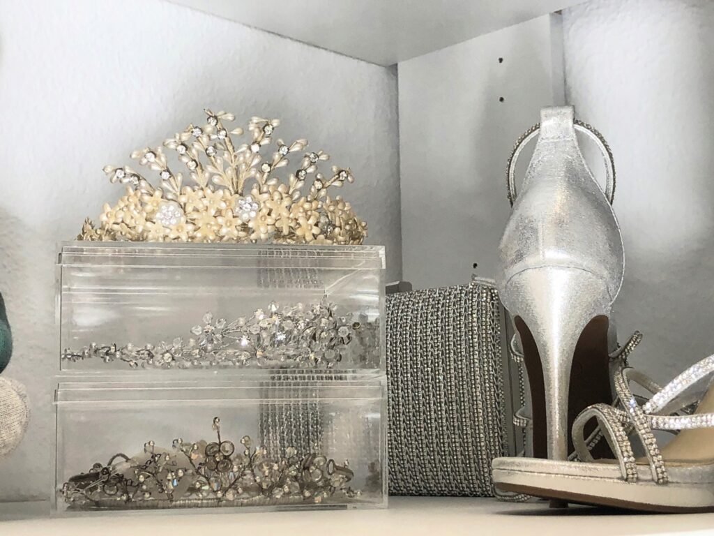 Decorative tiaras, silver clutch bags, and jeweled accessories neatly arranged on a white closet shelf.
